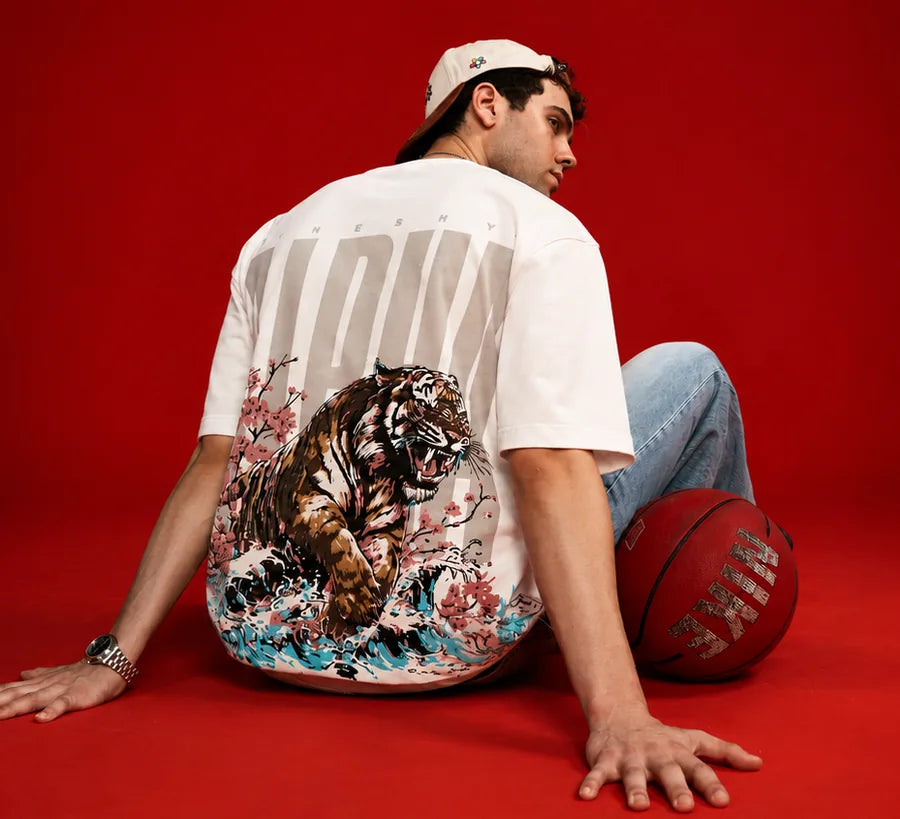 Alpha Tee — tiger back print on off-white, seated against a red backdrop