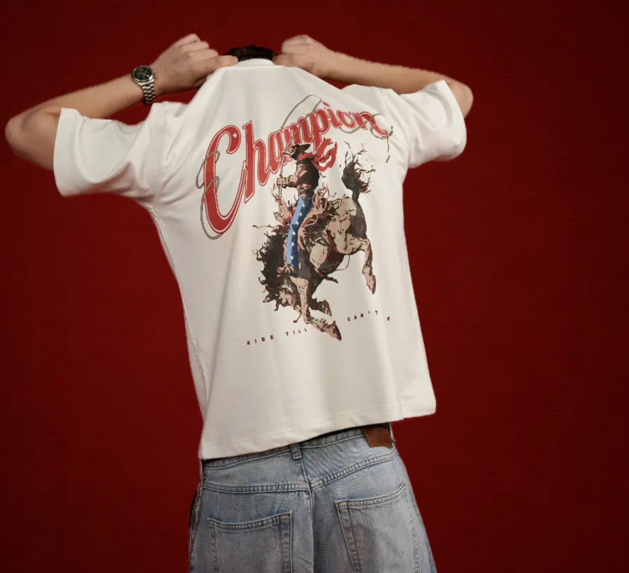 Champion Tee — vintage rodeo back print, worn against a deep red backdrop