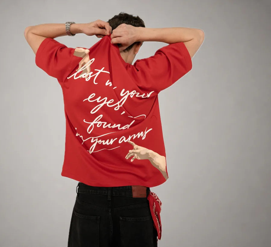 Lost Tee — script back print on red, against a grey studio backdrop