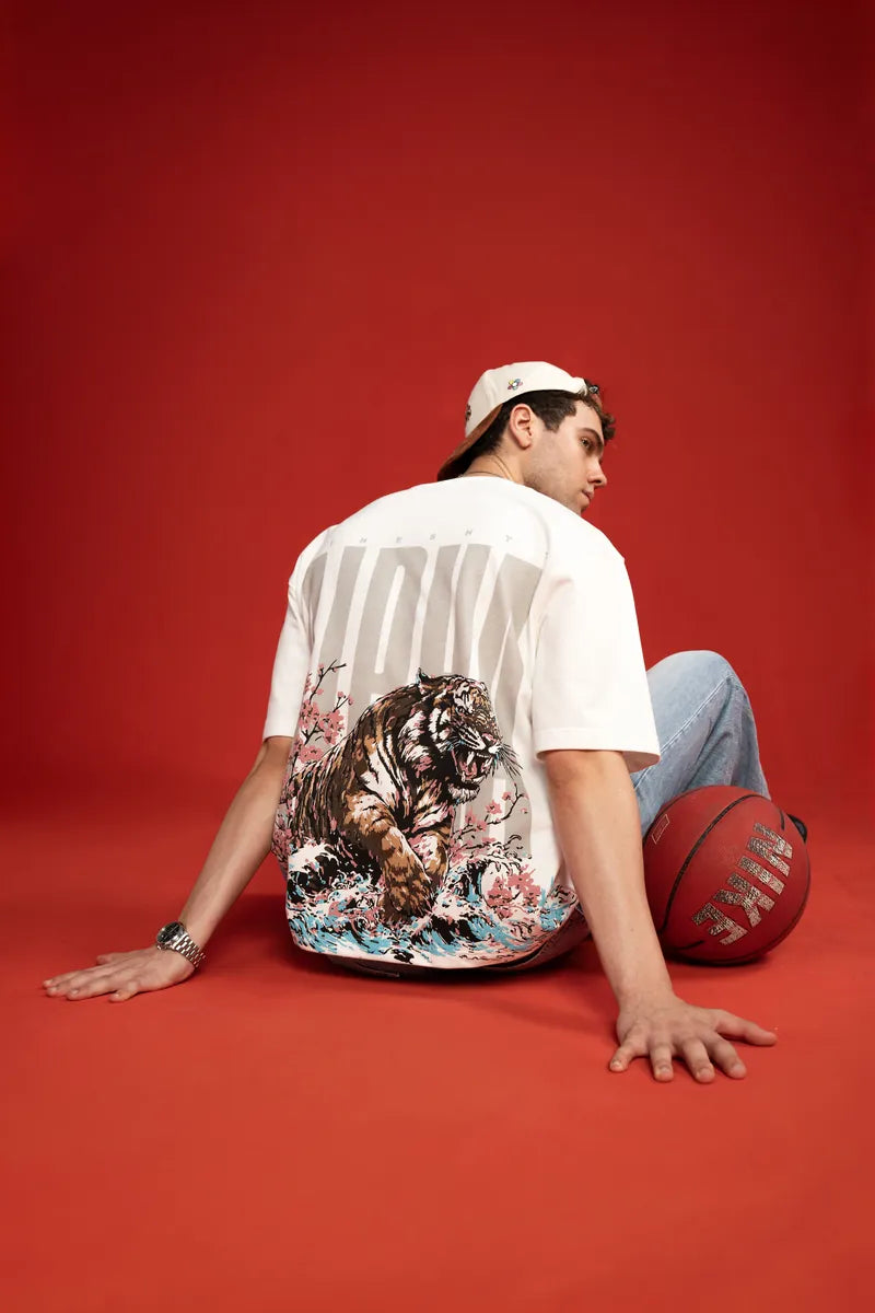 Seated in the Alpha Tee with a basketball, tiger back print on red
