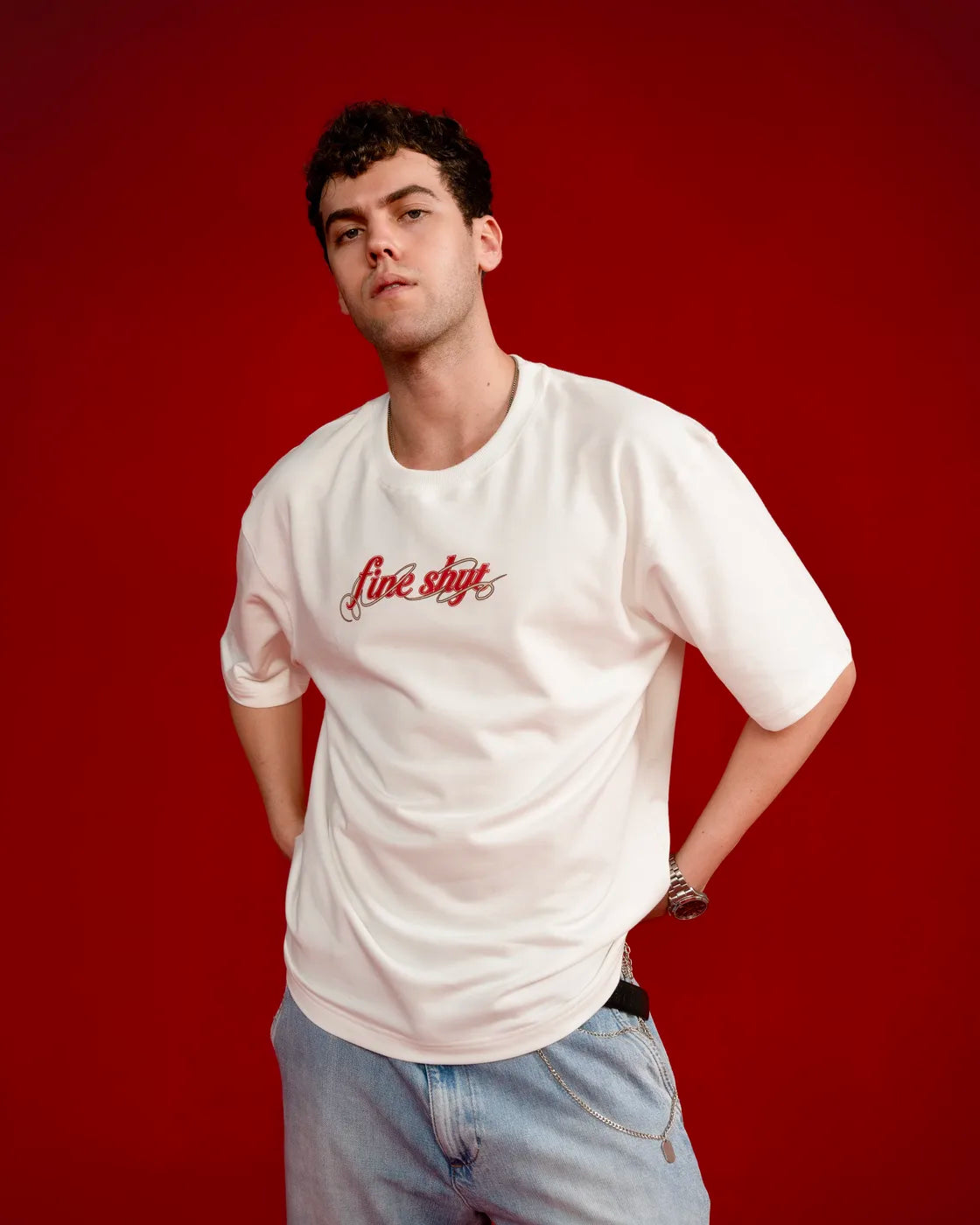 Model in the off-white Fine Shyt script tee against a red backdrop